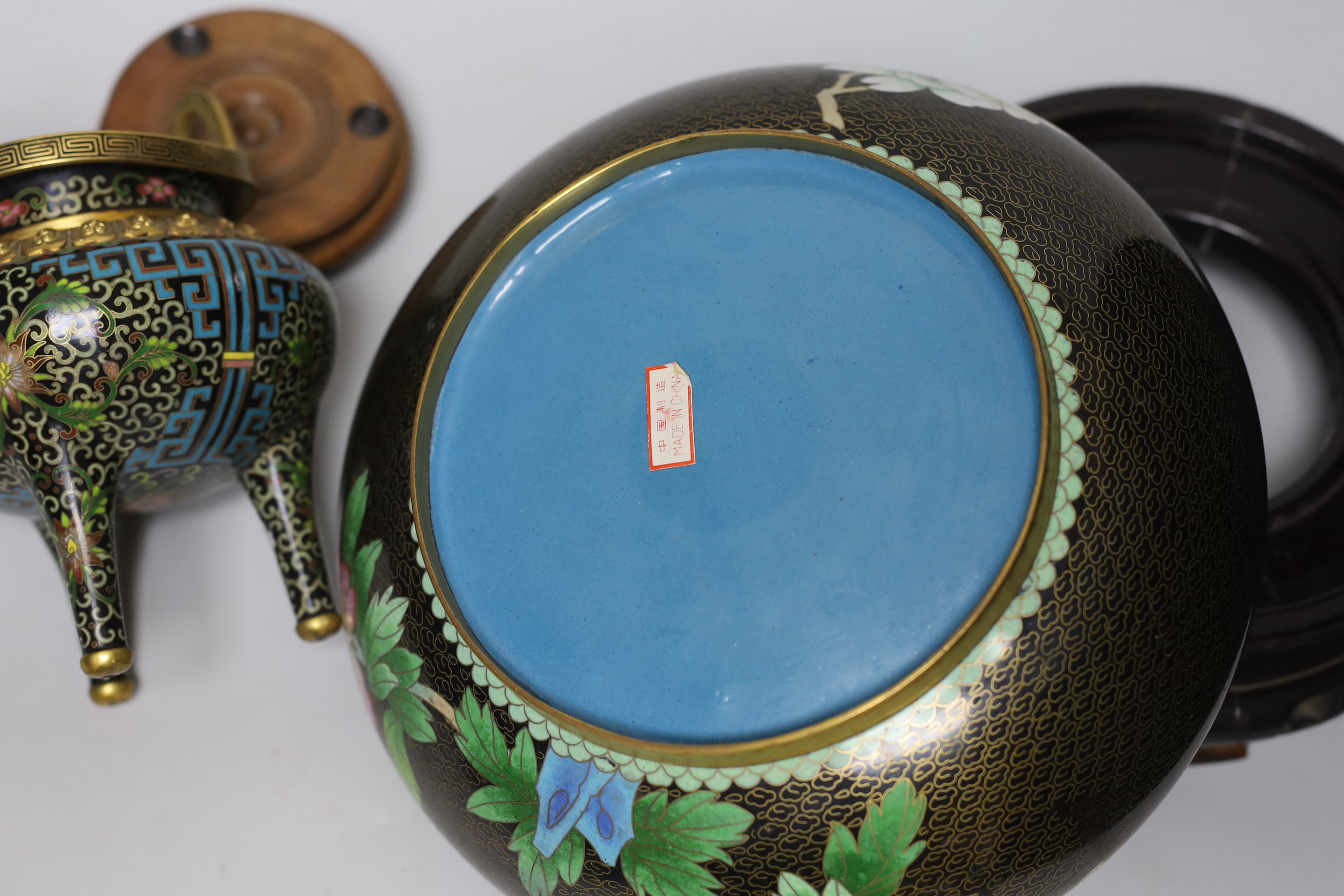 A Chinese cloisonné enamel three footed vase and cover together with a censer and cover, each raised on hardwood stands, the largest 26cm in diameter